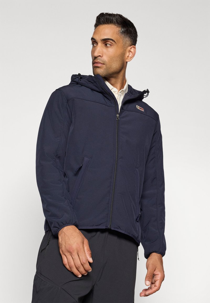 Chaqueta con capucha de color azul marino con cremallera, que presenta puños elásticos y bolsillos laterales. Tiene una textura suave y un pequeño logo en el pecho.