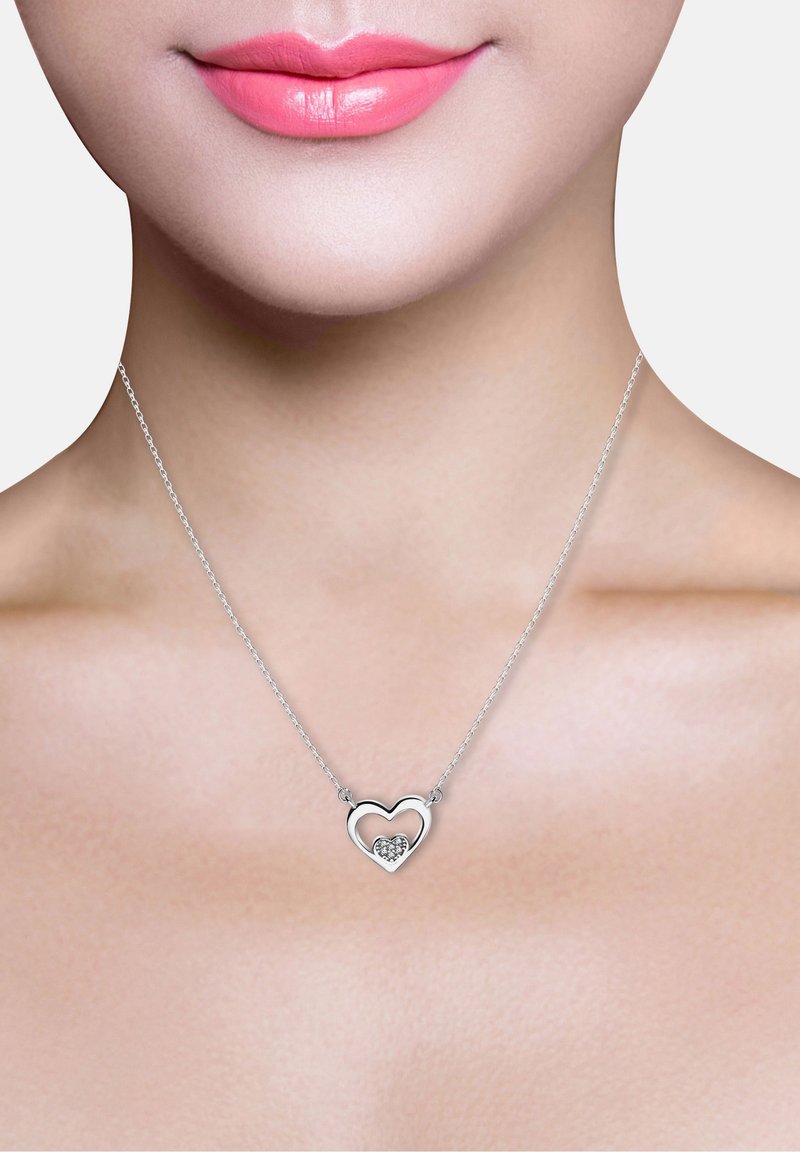 Silver hjärtformat halsband med ett inre hjärta och en liten kluster av stenar. Fin kedja, minimalistisk design.
