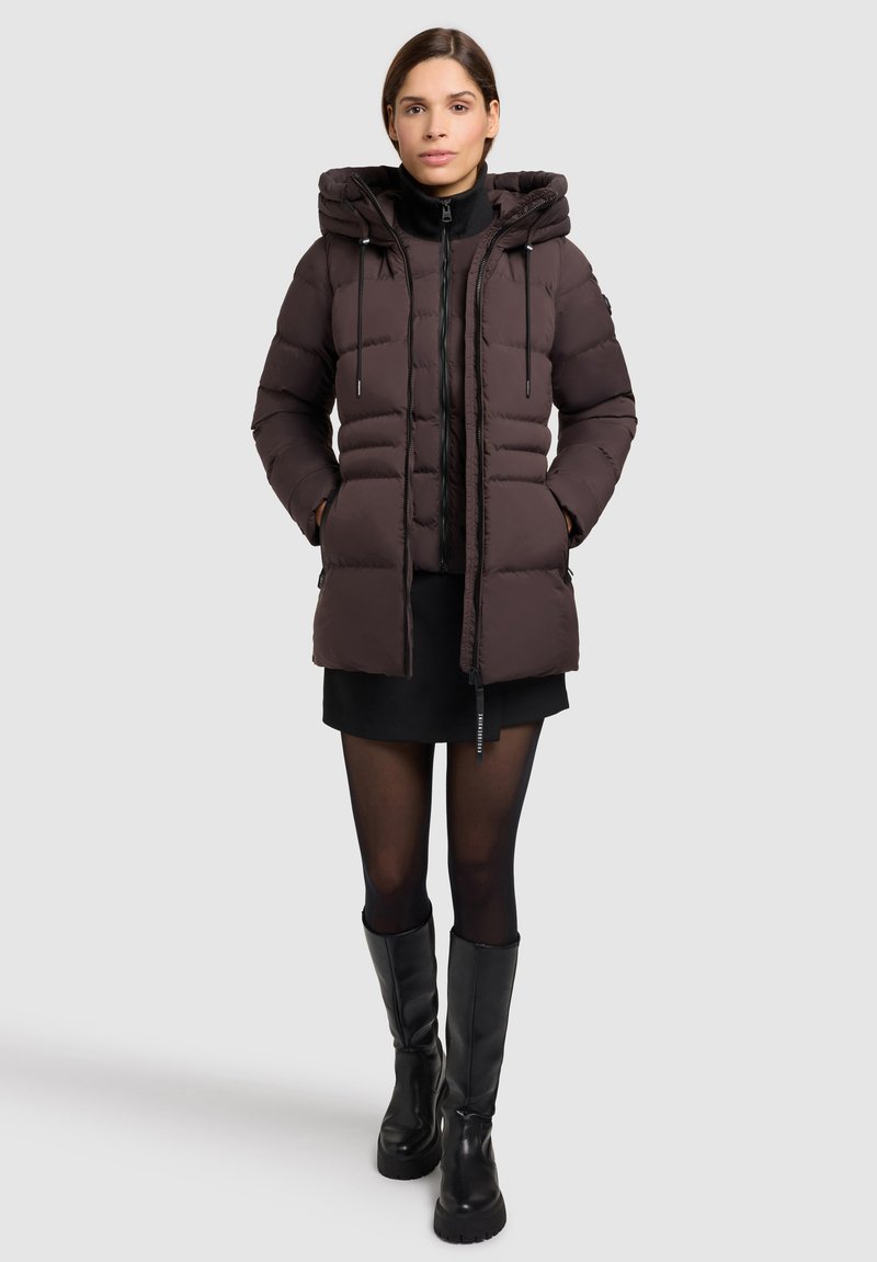 Giacca a vento marrone con cappuccio, chiusura con zip e cordini regolabili. Presenta un design trapuntato e due tasche laterali.