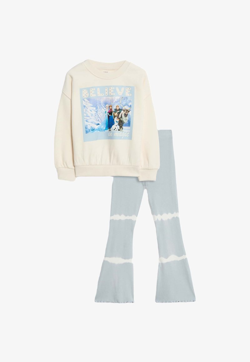 Felpa color crema con stampa grafica raffigurante personaggi e testo. Leggings azzurri svasati con motivo tie-dye.
