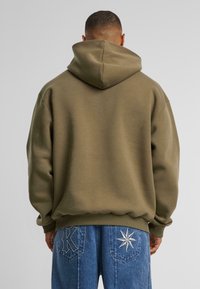 Olijfgroene hoodie met een ontspannen pasvorm, geribbelde manchetten en zoom. Draag het met blauwe jeans met geborduurde ster- en letterdetails.