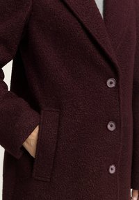 Bordeaux wollen blend jas met een textuurafwerking, enkelrijg ontwerp, twee knopen en zijzakken, met een geknipte kraag.