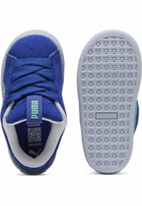 Plave atletske tenisice s teksturiranim gornjim dijelom, bijelim točkicama na midsole-u i gumeni potplat s geometrijskim uzorkom. Logo na jeziku i peti.