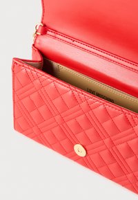 Κόκκινο πορτοφόλι από δερματίνη με σχέδιο καπιτονέ, με χρυσό κούμπωμα, εσωτερική τσέπη και επένδυση με λογότυπο.