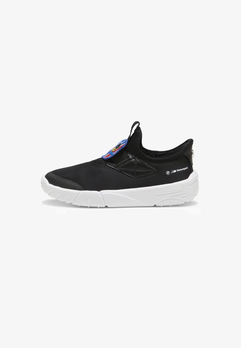 Black slip-on shoes with a textured upper, white soles, and a colorful logo patch. Features a pull tab for easy wear.