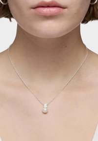 Collar de cadena de plata con un colgante de perla redonda. La perla tiene una superficie suave y un acabado lustroso, creando un brillo sutil.