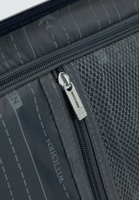 Gray fabric pouch with a textured, mesh pocket. Features a silver zipper pull with "WITTCHEN" engraved. Subtle airplane pattern on the material.