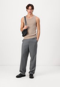 Beige ärmelloses Oberteil, graue Nadelstreifenhose und schwarze Umhängetasche. Die Schuhe sind schwarz mit dicker Sohle. Einfaches, tailliertes Design.