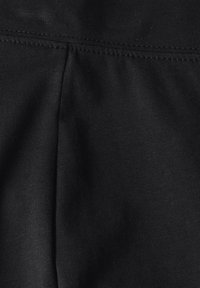 Svart tyg med en slät, stretchig textur. Har en söm och ribbade detaljer, vilket visar en jämn och enhetlig svart färg genomgående.