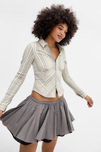 Bluză cu dungi, cu fermoar în față, de culoare crem și albastră, cu un design ajustat. Fustă mini gri fluidă, cu talie plisată și textură în straturi.