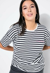 Černobíle pruhované tričko s krátkým rukávem, které má kulatý výstřih a růžový vyšitý text "vrátit to zpět." Měkká textilie.