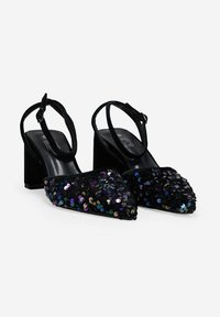 Zapatos de tacón alto negros tipo slingback con punta afilada, adornados con lentejuelas multicolores, y con una correa de terciopelo negro texturizado.