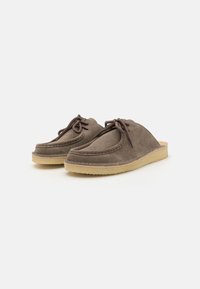 Brown suede slip-on shoes with a rounded toe, featuring a lace detail at the front and a light tan rubber sole.