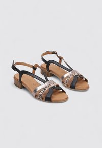 Sandales noires et bronze avec une bande à imprimé léopard, design à lanières, talon bas et semelle intérieure marron. Bride de cheville ajustable pour un bon maintien.