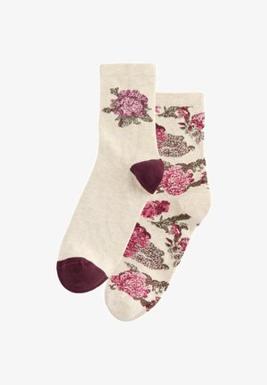 Chaussettes en coton beige avec des motifs floraux dans des nuances de rose et de vert, avec des accents bordeaux au niveau des orteils. Une chaussette est à motifs, l'autre est unie.