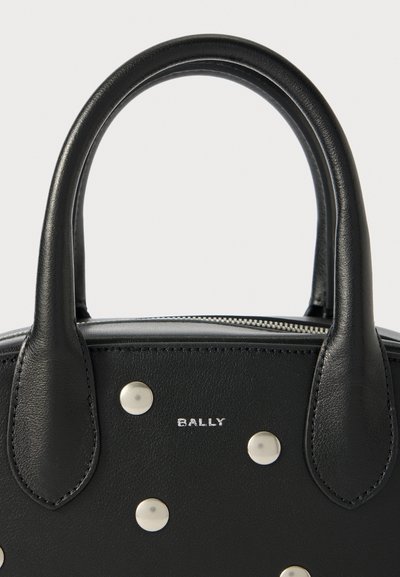 Black leather handbag with rounded handles. Features silver studs and a logo. Zipper closure. Smooth texture, compact shape.