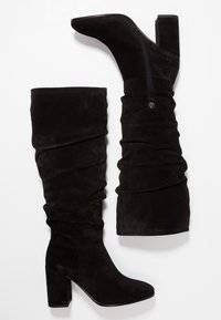 Svarta mocka stövlar över knäet med en slapp design, hög blockklack och sidodragkedjedetalj. Slät textur och kroppsnära passform.