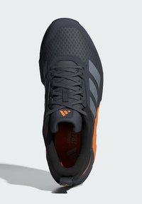 Must mustus jalanõud tekstuurse pealmise osaga, oranžide detailidega, halli kolmerealisusega disainiga ja mugavuse tagamiseks pehmendatud kraega.
