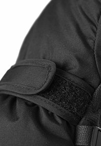 Svart tyghandske med en ärm som har en kardborrefästning och texturerat material. Slät textur med samlad tygdetalj.