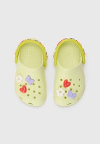 Crocs vert clair avec des charms décoratifs représentant des fleurs, des cœurs et des papillons ; design perforé et bride colorée à perles.