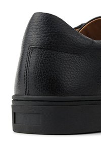 Czarny skórzany but o teksturowanym wykończeniu, zaokrąglonym tylnej części i czarnej gumowej podeszwie. Posiada subtelne przeszycia i płaski obcas.