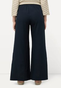 Pantalons à jambes larges en tissu bleu marine foncé, avec une taille élastique. L'ourlet est fini avec un bord net. Pas de motifs ou d'accents visibles.