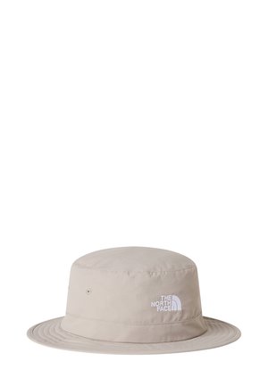 Sombrero tipo pescador de tela color beige claro, con ala ancha, detalles de costuras y un logo blanco en la parte frontal.