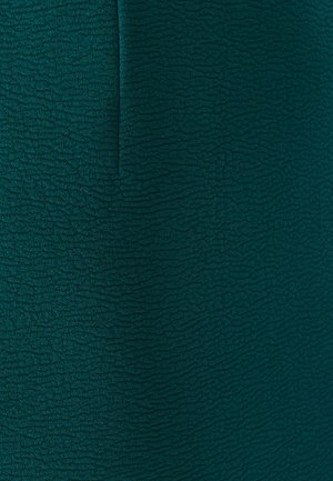 Tejido verde texturizado con un patrón ondulado. El material parece suave y ligeramente elástico, adecuado para prendas o tapicería.