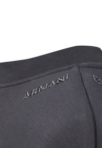 Sudadera gris oscuro con un cuello texturizado y el logotipo bordado "Armani" en el hombro. Tejido suave con un acabado liso.