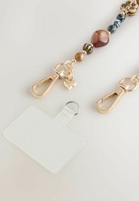 Șnur cu mărgele, prevăzut cu cleme din metal auriu, un charm decorativ în formă de inimă și un suport transparent pentru ID cu un inel metalic.