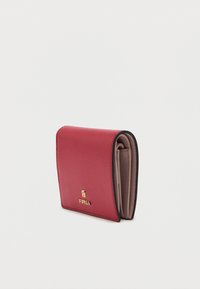 Czerwony skórzany portfel o teksturowanym wykończeniu, z beżowym wnętrzem, złotymi detalami logo oraz kompaktowym, składanym designem.