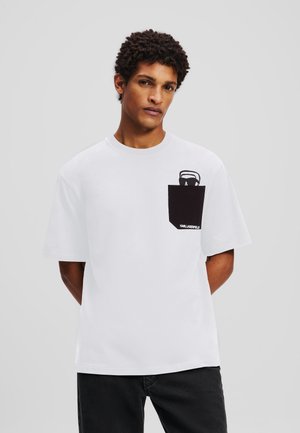 Witte katoenen T-shirt met korte mouwen, voorzien van een zwarte zak met een illustratie en logo. Eenvoudig ontwerp met ronde hals.