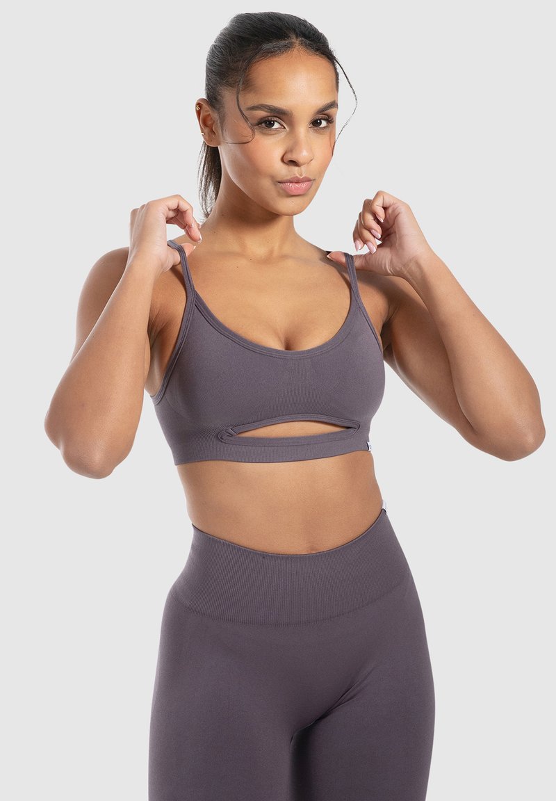 Grijze sport-bra met dunne bandjes en een uitgesneden ontwerp. Gemaakt van rekbaar materiaal, met een naadloze afwerking voor comfort.
