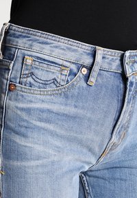 Ljusblå denimjeans med en urtvättad look, med en klassisk femficksdesign, synlig sömnad och metallbeslag.