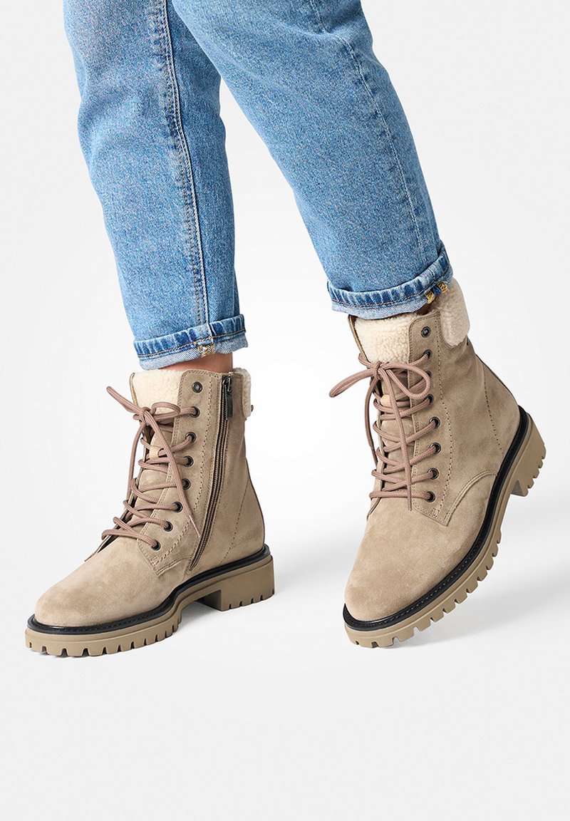 Bottines en nubuck beige avec une fermeture éclair sur le côté, un laçage à l'avant, un revers en fourrure et une semelle en caoutchouc épaisse avec un motif de semelle texturée.
