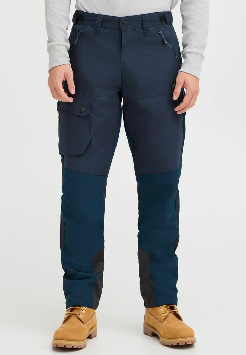 Navy outdoor pants featuring a zippered pocket, cargo-style front pocket, and dark accents; paired with tan boots for contrast.