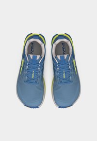 Ζευγάρι μπλε και κίτρινων παπουτσιών για τρέξιμο σε μονοπάτια με κορδόνια, γκρι εσωτερικές σόλες και θηλιές στο πίσω μέρος, απόψη σε λευκό φόντο.