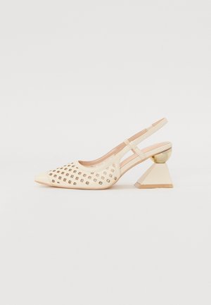 Beige slingback sko med udskåret kvadratisk mønster foran og geometrisk hæl, der kombinerer en gylden kugle og en bred trapezform.