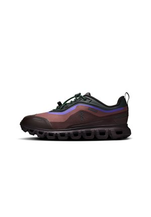 Chaussure de course outdoor marron et noire avec des accents violets, dotée d’une semelle épaisse et de lacets élastiques verts pour un maintien sécurisé et une bonne adhérence.