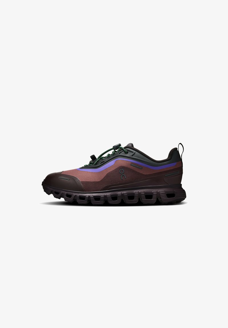 Chaussure de course outdoor marron et noire avec des accents violets, dotée d’une semelle épaisse et de lacets élastiques verts pour un maintien sécurisé et une bonne adhérence.