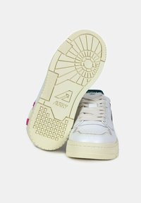 Sneaker bianche in pelle con suola testurizzata, caratterizzate da accenti rosa e verde. Il design include motivi a battistrada tondeggianti e quadrati.