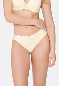 Braguitas de bikini color crema con un patrón floral, con una textura suave y detalles de encaje en la cintura y un lazo central.