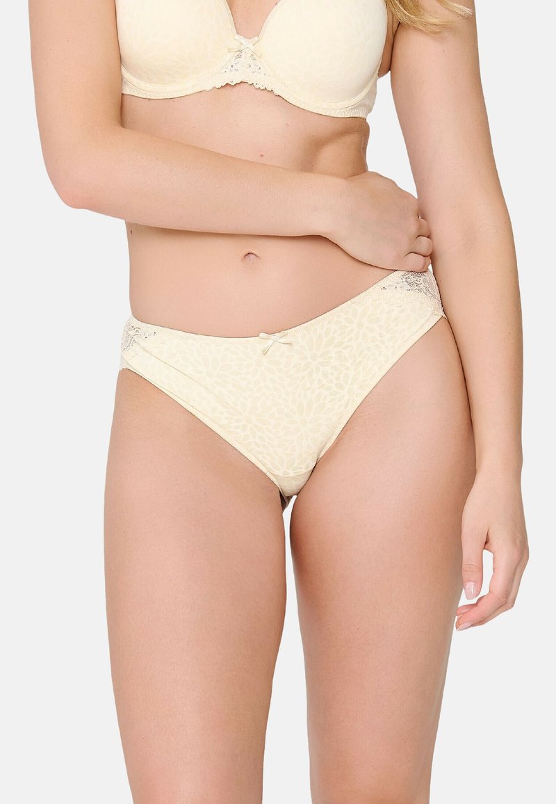 Braguitas de bikini color crema con un patrón floral, con una textura suave y detalles de encaje en la cintura y un lazo central.