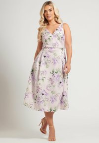 Blommig midiklänning i mjuk rosa med lila och gröna blommönster. Har V-ringning, figursydd midja och A-linjeformad kjol.