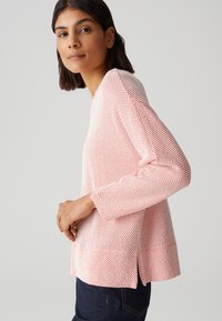 Pullover mit strukturiertem Strickmuster in Rosa und Weiß, mit langen Ärmeln, einem rundem Ausschnitt und seitlichen Schlitzen am Saum.