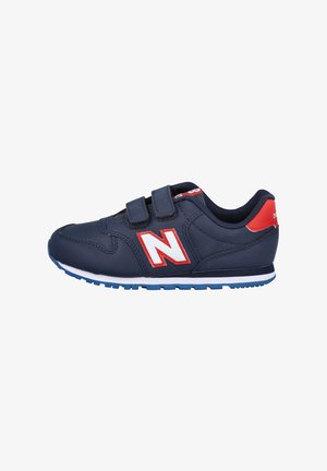 Zapatilla azul marino con correas de velcro, acentos en blanco y rojo, suela de goma, detalles de tela de malla y logo de New Balance en el costado.