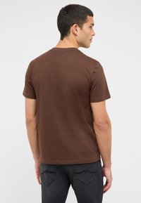 Brązowy, krótki rękaw T-shirt z bawełny, z okrągłym dekoltem i prostą, gładką fakturą. Tył ozdobiony jest starannie wykończonym brzegiem.