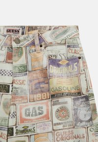Denim shorts met een multicolor patchwork van vintage labels en logo's, met een vervaagde textuur en metalen hardware accenten.