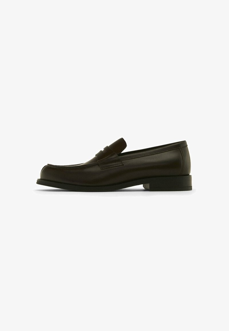 Bruine leren loafers met een gladde afwerking, een ronde neus en een licht verhoogde zwarte zool. Bevat een decoratieve strap over de wreef.