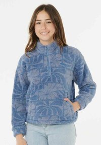 Blå fleecepullover med halv-zip foran, strikket stof og blomstermønstre. Har lange ærmer og sidelommer.
